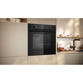 Neff black built-in single electric oven installed in cream fitted kitchen cabinetry, shown in lifestyle setting.