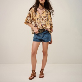 Model wearing Bash yellow leopard-print oversized blouse with denim shorts, brown belt and lace-up flat sandals