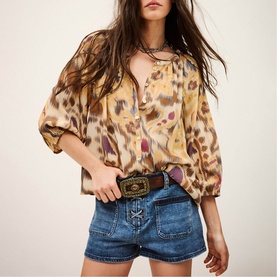 Model wearing Bash yellow leopard-print blouse with balloon sleeves, styled with denim shorts and embellished belt