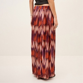 Model wearing Bash orange ikat-print maxi skirt with elasticated waist, styled with a black top, rear view
