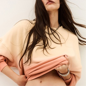 Model wearing Bash yellow cropped sweatshirt, styled with a silver chain necklace and bracelets