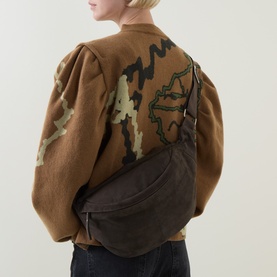 Model carrying InWear Rasida Suede Belt Bag in Chocolate Brown, worn crossbody with wide strap over a brown patterned jacket.