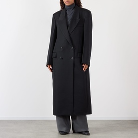 Model wearing Rohe Double-Breasted Tailored Coat in black wool with peaked lapels and structured shoulders, styled with grey wide-leg trousers.