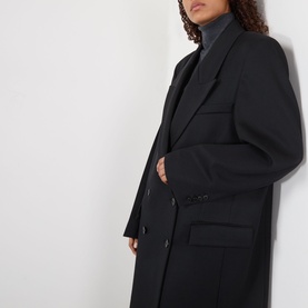 Model wearing Rohe Double-Breasted Tailored Coat in black wool, featuring peaked lapels and structured shoulders, styled with a grey roll-neck.