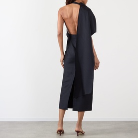 Model wearing Rohe Cape Pencil Dress in Night, showing open back, asymmetric cape detail and midi length, styled with tan heeled mules.