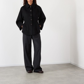 Model wearing Rohe Double-Faced Sculptural Jacket in black with pointed collar, cinched waist, and oversized sleeves, styled with wide-leg trousers.
