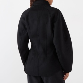 Model wearing Rohe Double-Faced Sculptural Jacket in black, rear view showing cinched waist, oversized sleeves and back darts, styled with black