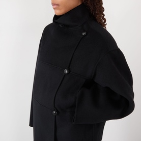 Model wearing Rohe Double-Faced Asymmetric Jacket in black with funnel neck and off-centre button fastening