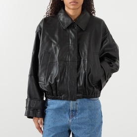 Model wearing Rohe black leather bomber jacket with collar, elasticated hem and cuffs, styled with blue denim jeans.