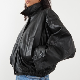 Model wearing Rohe black leather bomber jacket with elasticated hem, button cuffs, and high neck, styled with blue jeans.