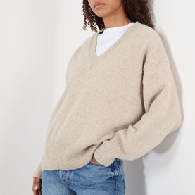 Model wearing Rohe Classic Moulin&eacute; Sweater in Oat Melange, V-neck with dropped shoulders, styled with white shirt and blue jeans.