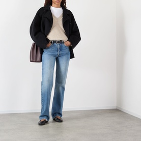 Model wearing Rohe Classic Moulin&eacute; Sweater in Oat Melange with blue straight-leg jeans, black jacket and grey loafers