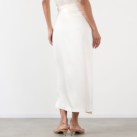 Model wearing Rohe ivory midi skirt in satin-finish fabric, styled with nude mule heels, rear view showing bias-cut hem.