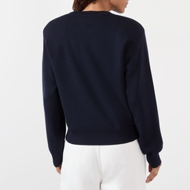 Model wearing Rohe Statement Knit Sweater in navy, crew neck, long sleeves, ribbed trims; back view styled with white trousers.