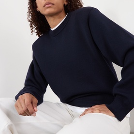 Model wearing Rohe Statement Knit Sweater in navy, crew neck, long sleeves, ribbed trims, styled with white trousers.