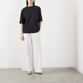 Model wearing Rohe Anthracite Melange merino wool T-shirt, styled with wide-leg white trousers and strappy heeled sandals.