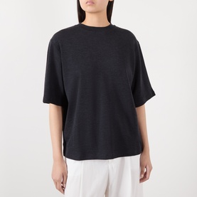 Model wearing Rohe merino wool T-shirt in Anthracite Melange, relaxed boxy fit with crew neck and short sleeves, styled with white trousers