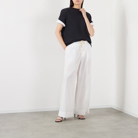 Model wearing Rohe Anthracite Melange merino wool T-shirt with white wide-leg trousers and black heeled sandals.