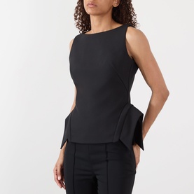 Model wearing Rohe Deconstructed Peplum Top in black, featuring boat neckline, sleeveless cut and peplum hem, styled with black trousers