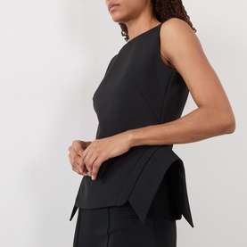 Model wearing Rohe Deconstructed Peplum Top in black, sleeveless with boat neckline, structured peplum hemline and deconstructed seam details