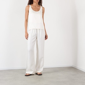 Model wearing Rohe Solid Fluid Top in ivory, sleeveless satin with scoop neck, styled with matching wide-leg trousers and brown sandals.