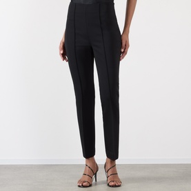 Model wearing Rohe black slim-leg trousers with satin waistband detail, styled with strappy heeled sandals.