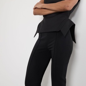 Model wearing Rohe black tailored trousers with fold-over waistband detail, slim leg silhouette, styled with a black top.