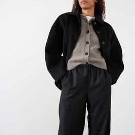 Model wearing Rohe Wide Leg Trousers in Anthracite Melane, styled with a grey knit cardigan and black jacket.