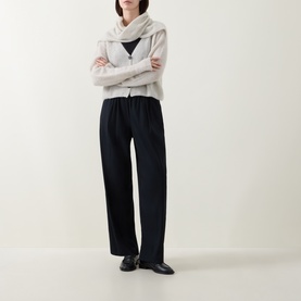 Model wearing Sarah Pacini cream cardigan with wide-lapel collar, styled with black wide-leg trousers and black leather loafers.
