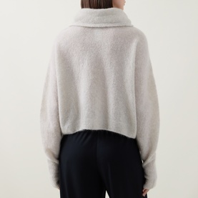 Model wearing Sarah Pacini cream cardigan, back view, with wide collar and fluffy texture, styled with black wide-leg trousers.