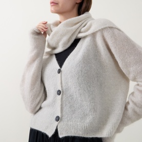 Model wearing Sarah Pacini cream cardigan with draped scarf collar detail, styled over a dark dress.