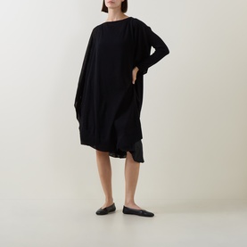 Model wearing Sarah Pacini Knitted Oversized Tunic Dress in black with asymmetric hem and boat neck, styled with black flat shoes