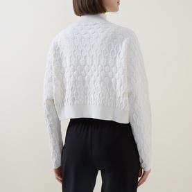 Model wearing Sarah Pacini Honeycomb Knit Zip Cardigan in white, showing textured back detail and cropped boxy fit, styled with black trousers.