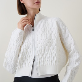 Model wearing Sarah Pacini Honeycomb Knit Zip Cardigan in white, showing textured pattern, funnel neck and two-way zip fastening