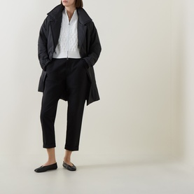 Model wearing Sarah Pacini Honeycomb Knit Zip Cardigan in white, styled with black oversized coat, trousers and flat loafers.
