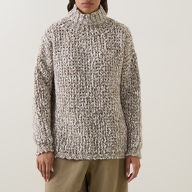 Model wearing Sarah Pacini beige chunky knit turtleneck sweater with textured weave pattern, styled with khaki trousers