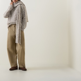 Model wearing Sarah Pacini beige chunky knit sweater with draped scarf detail, styled with khaki wide-leg trousers and brown loafers