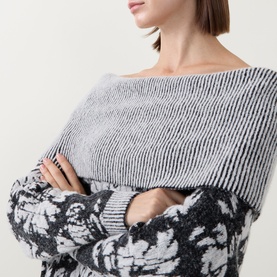 Model wearing Sarah Pacini black knit jumper with contrast stripe yoke and floral jacquard sleeves, arms crossed.