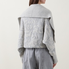Model wearing Sarah Pacini cream knitwear with wide lapel collar and floral jacquard pattern, styled with grey wide-leg trousers, rear view.