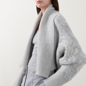 Model wearing Sarah Pacini cream knit wrap cardigan with textured floral sleeves and ribbed collar, styled with grey trousers