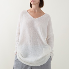 Model wearing Sarah Pacini cream knit jumper with V-neck and relaxed fit, styled with grey wide-leg trousers