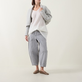 Model wearing Sarah Pacini cream oversized knit cardigan, styled with white top, grey striped wide-leg trousers and taupe flat mules.