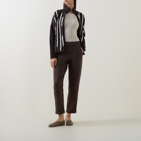 Model wearing Sarah Pacini brown tapered trousers, styled with a monochrome textured jacket and khaki loafers.