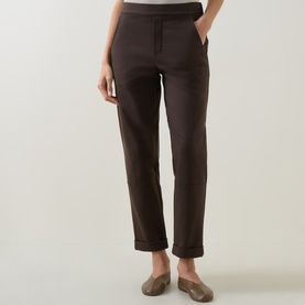 Model wearing Sarah Pacini brown trousers with turn-up hems and side pockets, styled with flat metallic loafers.