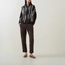 Model wearing Sarah Pacini brown tailored trousers, styled with a black and white striped knit jacket and brown loafers.
