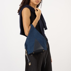 Model carrying Stella McCartney Appaloosa Bucket Bag in navy, geometric faux suede design with gold-tone hardware and zip fastening, styled with