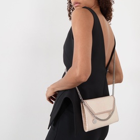 Model carrying Stella McCartney Falabella Chain Wallet in Shell Pink with silver-tone chain strap and trim, styled with black open-back dress