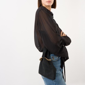 Model carrying Stella McCartney Falabella Pouch in black suede finish with gold-tone chain, styled with sheer black blouse and blue jeans
