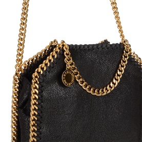 Stella McCartney black crossbody bag with chunky gold chain straps and trim, logo charm pendant, textured faux-leather finish.