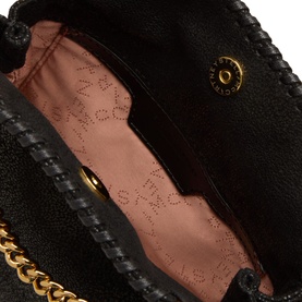 Stella McCartney black crossbody bag interior showing blush pink logo lining and gold chain strap detail with whipstitch edging visible.